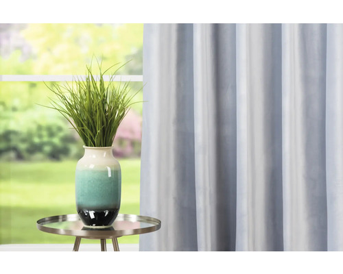 Dekorativní pokoj s modrým závěsem, stolem a vázou se zelenou rostlinou.