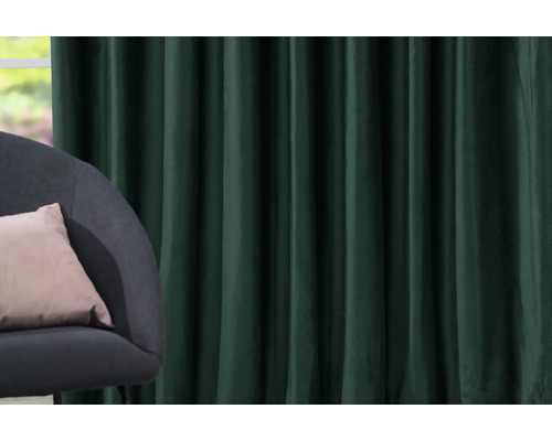 Dekorativní zelený závěs vedle křesla s polštářem.
