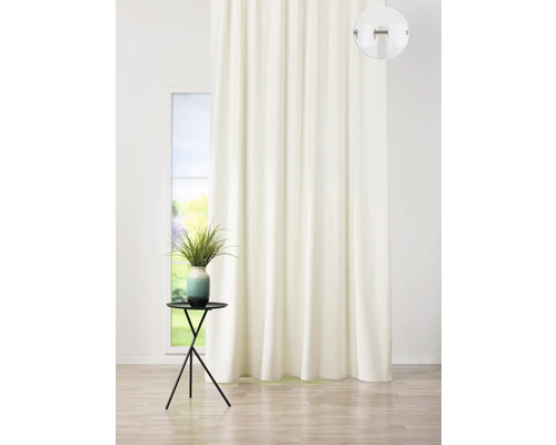 Béžový závěs před oknem a váza s květinami na malém stolku