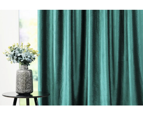 Dekorativní závěs a váza s květinami na stole.