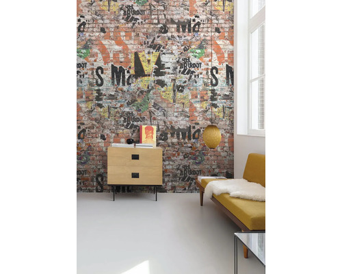 Obývací pokoj s tapetou na zdi s designem cihlové zdi, zdobenou graffiti, komoda, lampa a žlutá pohovka.