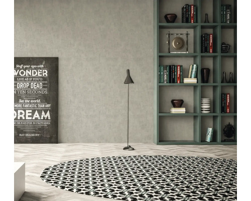 Obývací pokoj s kulatým kobercem, stojací lampou, regálem a dekorativním písmem