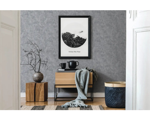 Moderní interiér s šedou tapetou, dřevěnou komodou a dekorativními prvky.