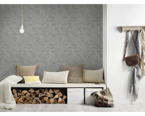 Interiér s šedou strukturovanou tapetou, lavicí s polštáři a poleny