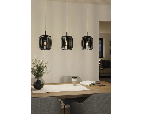 Tři kovová závěsná svítidla nad jídelním stolem.