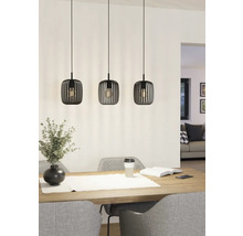 Tři kovová závěsná svítidla visí nad jídelním stolem a poskytují světlo.