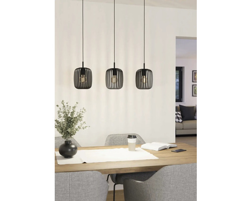 Tři kovová závěsná svítidla visí nad jídelním stolem a poskytují světlo.