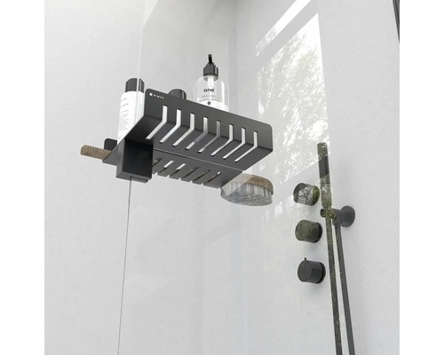 Černá sprchová police se šamponem, mýdlem a kartáčem připevněná ke sprchové stěně