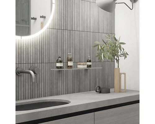 Moderní koupelna s umyvadlem, baterií, zrcadlem, policí a kosmetickými produkty před stěnou s vertikálními obklady