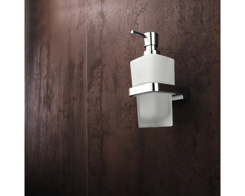 Skleněný a kovový dávkovač mýdla pro montáž na stěnu v koupelně.