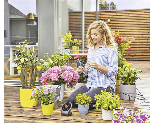 Žena stříhá zavlažovací hadici pro rostliny na terase