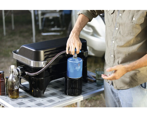 Osoba připojuje plynovou láhev ke grilu na plyn