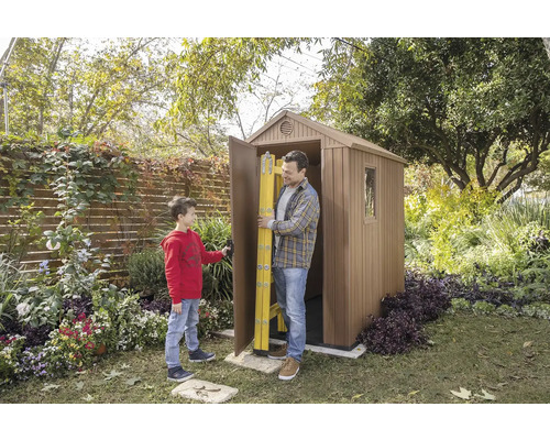 Muž a chlapec před zahradním domkem s otevřenými dveřmi, ve kterých je žebřík.