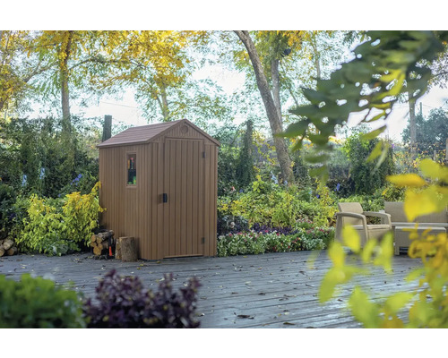 Plastový zahradní domek s oknem a dveřmi na terase v zahradě.