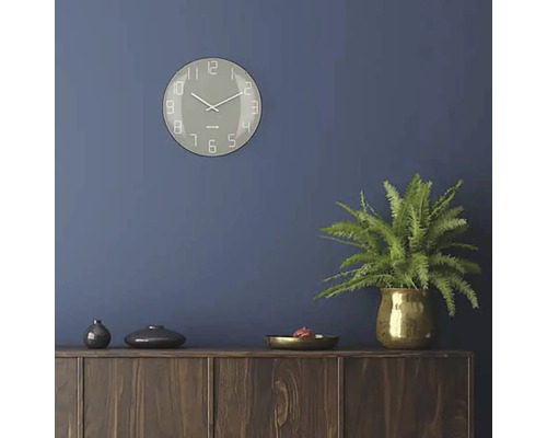 Obývací pokoj s nástěnnými hodinami, pokojovou rostlinou a dřevěnou komodou