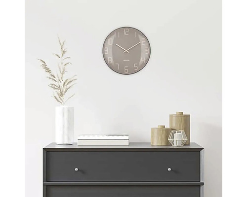 Dekorativní scéna s kulatými nástěnnými hodinami nad komodou.