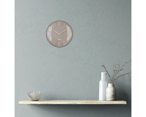 Nástěnné hodiny s ciferníkem na polici s dekoracemi