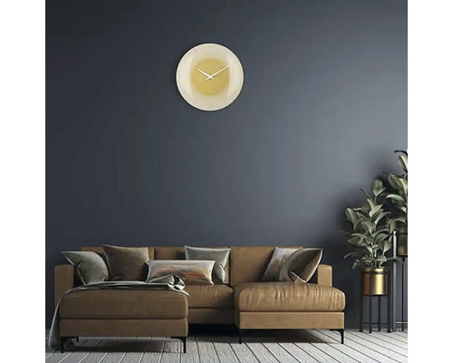 Obývací pokoj s pohovkou, pokojovou rostlinou a kulatými nástěnnými hodinami