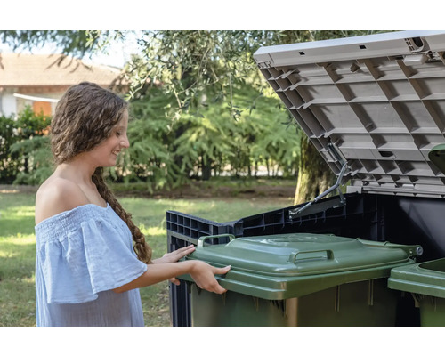 Žena umisťuje odpadkový koš do úložného boxu na popelnice na zahradě