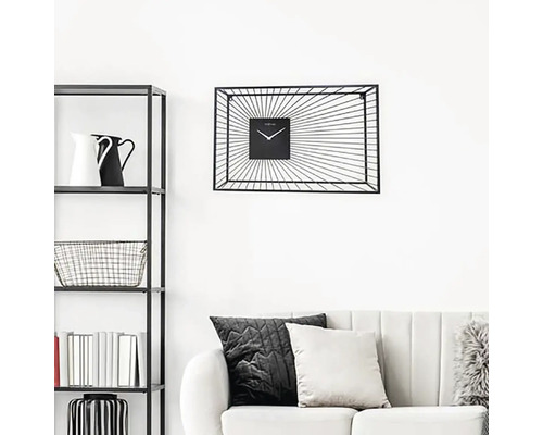 Obývací pokoj s regálem, pohovkou a černými nástěnnými hodinami