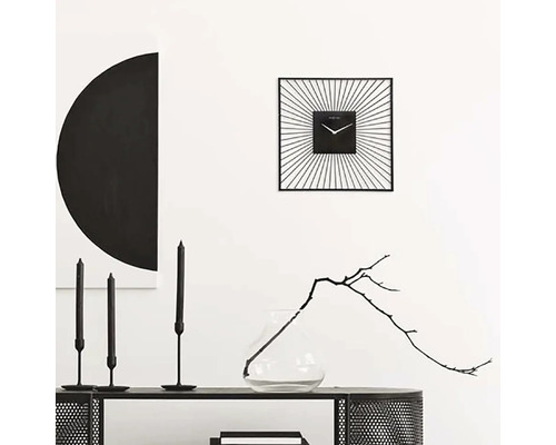 Dekorativní interiér se čtvercovými nástěnnými hodinami, svíčkami a vázou s větvičkou