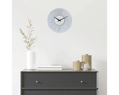 Dekorativní nástěnné hodiny nad komodou s bytovými doplňky