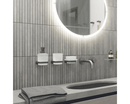 Moderní koupelna s kulatým zrcadlem, umyvadlem, baterií, dávkovačem mýdla, kelímkem na zubní kartáčky, mýdlenkou a ručníkem