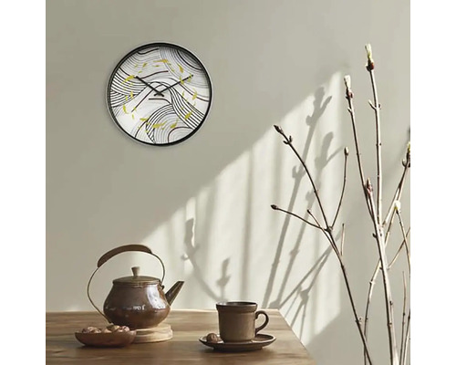 Nástěnné hodiny s abstraktním vzorem nad konvicí a šálkem na stole