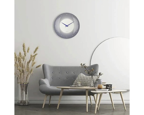 Obývací pokoj s šedou pohovkou, dřevěnými stolky a kulatými nástěnnými hodinami