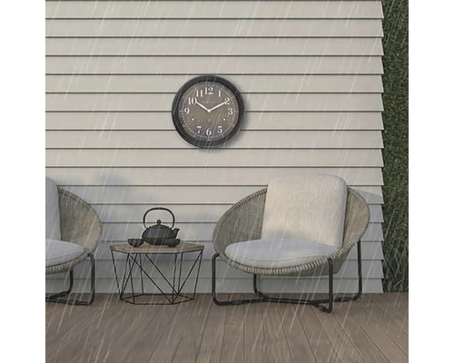 Scéna s nástěnnými hodinami, dvěma židlemi a stolem venku v dešti.