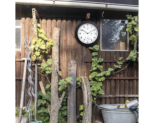 Venkovní scéna s nástěnnými hodinami, vinnou révou, zahradním nářadím a dřevěným plotem