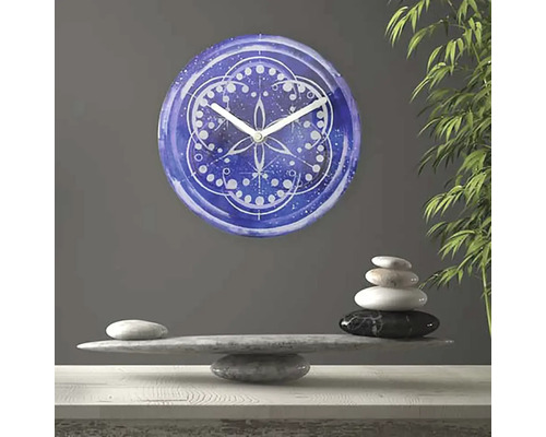 Dekorativní nástěnné hodiny s mandalovým vzorem nad hromadou kamenů