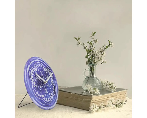 Stolní hodiny se vzorem vedle květin a knihy