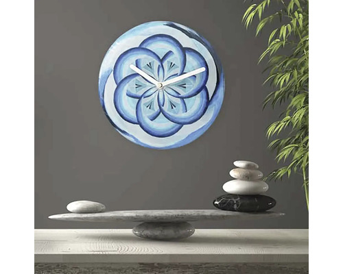 Nástěnné hodiny s modrým květinovým vzorem vedle kamenné rovnováhy