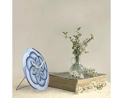 Stolní hodiny s modrým květinovým vzorem na knize vedle vázy s květinami
