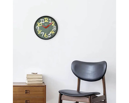 Nástěnné hodiny s ciferníkem a číslicemi nad dřevěnou skříňkou a židlí