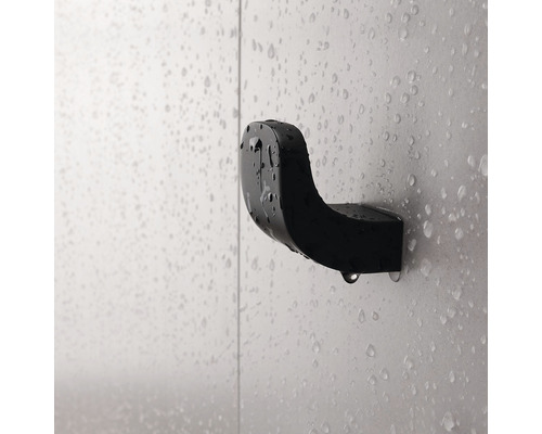 Černý háček na župan na zdi s kapkami vody