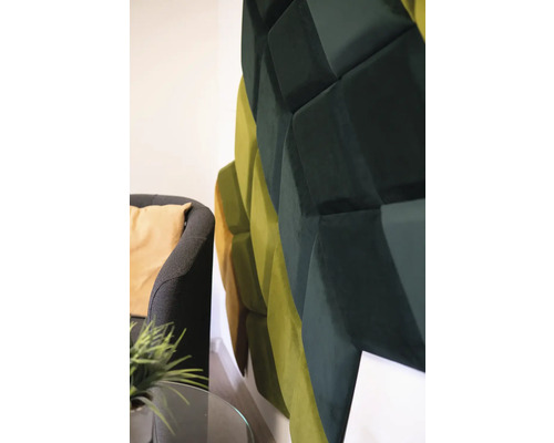 Nástěnný panel s trojrozměrným geometrickým designem vedle křesla.