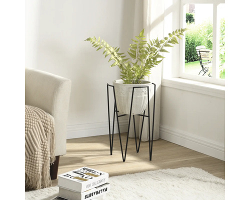 Pohled do pokoje s rostlinou v květináči na kovovém stojanu.