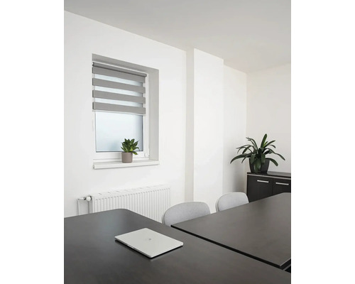 Světlá kancelář s oknem, roletou, stolem a notebookem