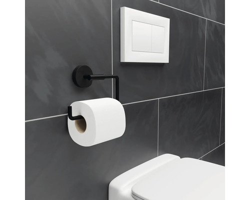 Kovový držák toaletního papíru s rolí toaletního papíru vedle splachovače toalety