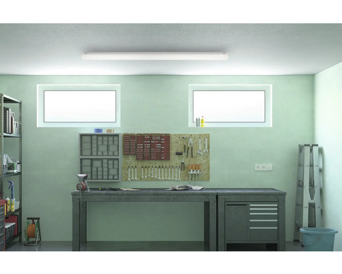 Dílna s pracovním stolem, stěnou na nářadí a policemi pod stropním svítidlem.