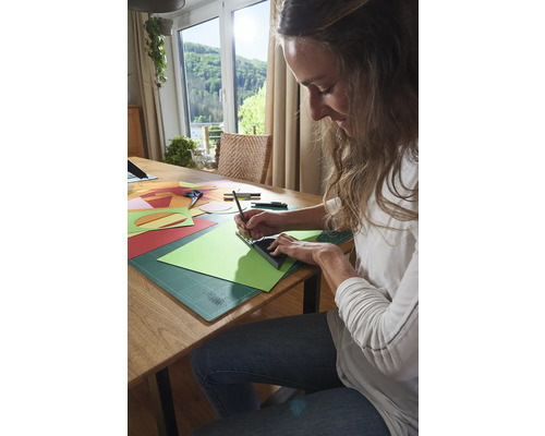 Žena pracuje s papírem, pravítkem a tužkou u stolu.