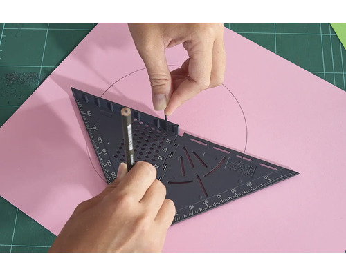 Osoba kreslí kruh na růžový list papíru pomocí tužky a trojúhelníku.