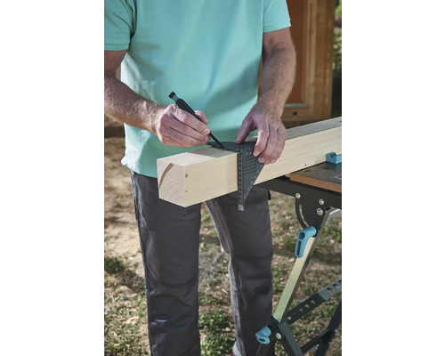 Řemeslník kreslí značku na dřevěné desce pomocí úhelníku a tužky.