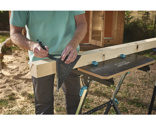 Osoba označuje kus dřeva pomocí úhelníku a tužky na pracovním stole.