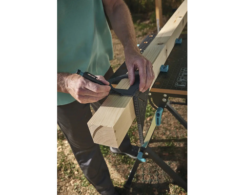 Osoba označuje kus dřeva úhelníkem na pracovním stole.