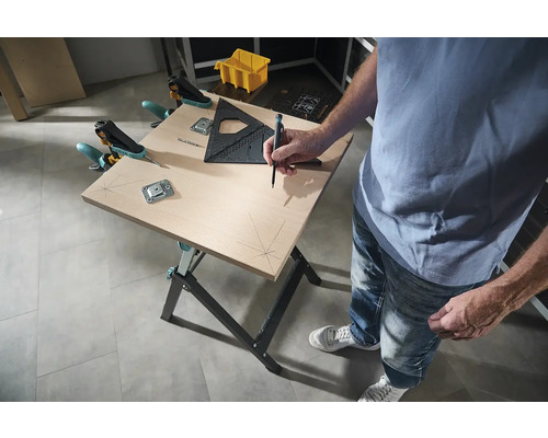 Pracovní stůl s osobou, která tužkou kreslí čáry na dřevěnou desku, s úhelníkem a svorkami pro upevnění