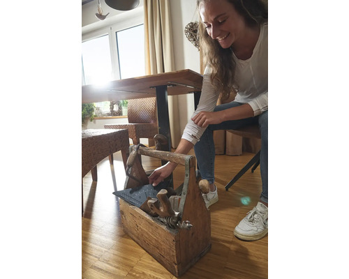 Žena sahá do dřevěné bedny na nářadí s různým nářadím