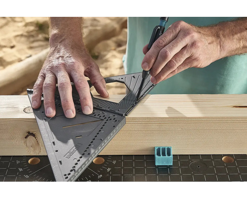 Osoba rýsuje čáru na kusu dřeva pomocí úhelníku a tužky.